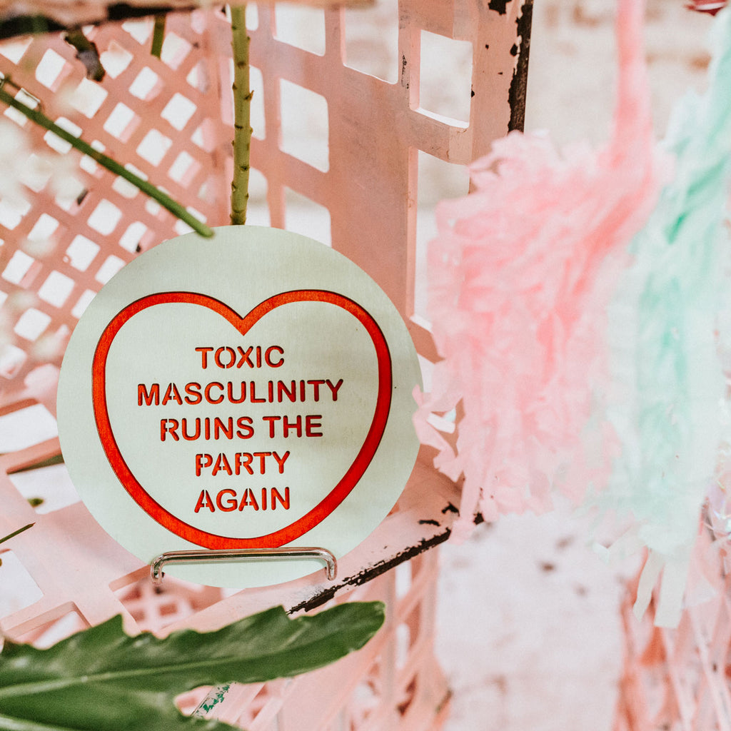 Candy & Kitsch candy heart wall hanging sits in a kitsch interior design in the variation ’toxic masculinity ruins the party again' inspired by my favorite murder