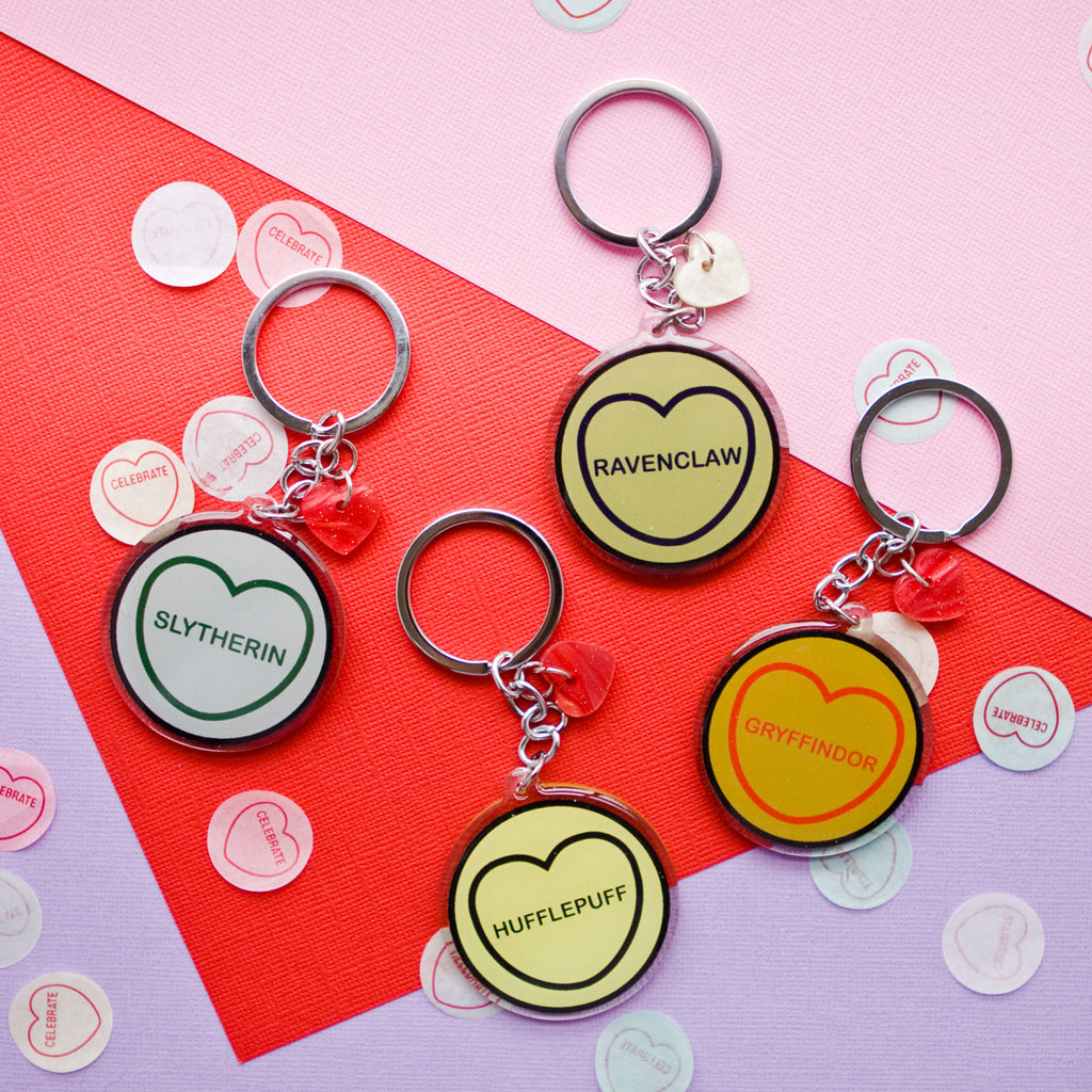 candy and kitsch harry potter candy hearts hogwarts houses keyrings sits in a colourful background with candy heart confetti