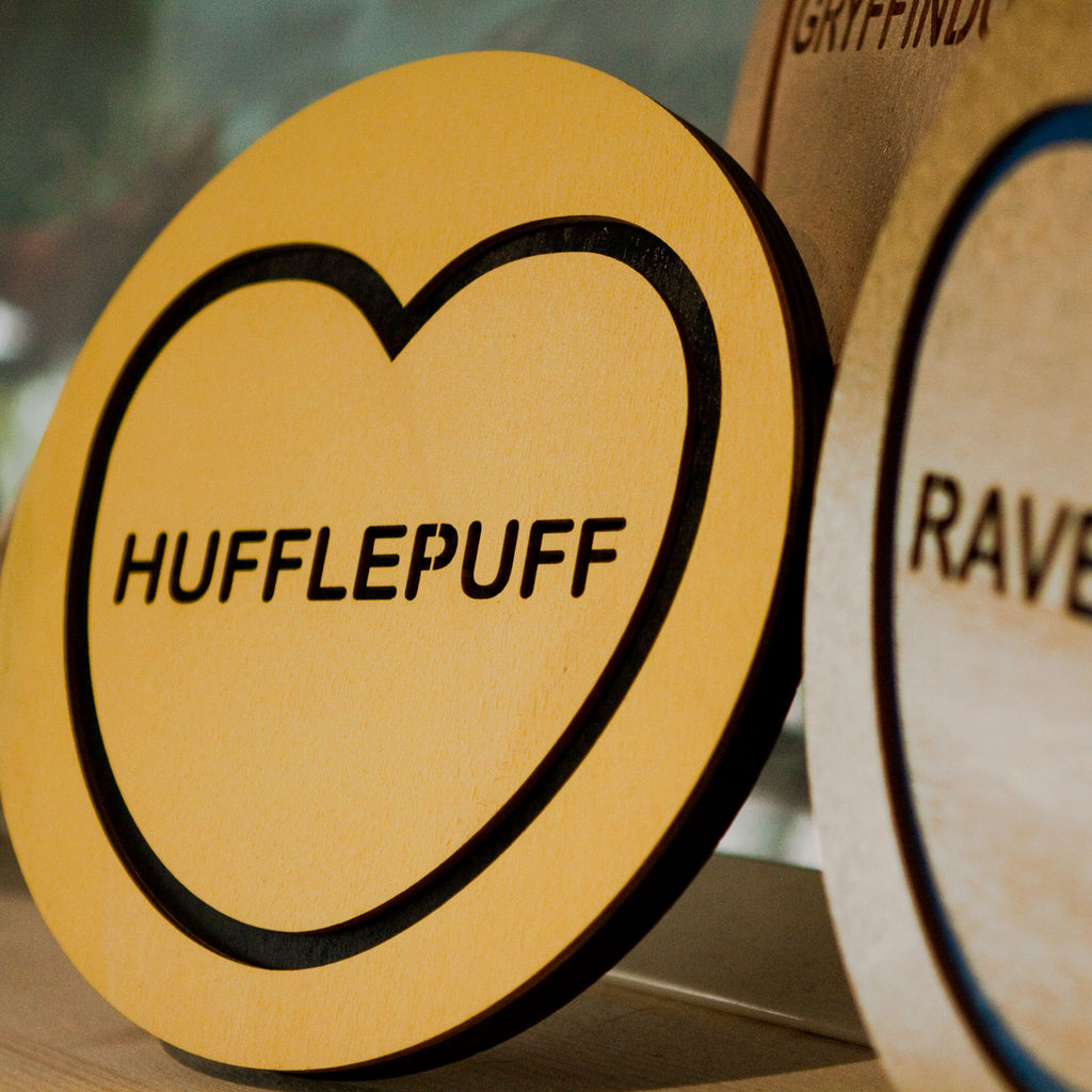Candy & Kitsch harry Potter hogwarts houses wall hangings sitting in a room together, featuring the hufflepuff variation