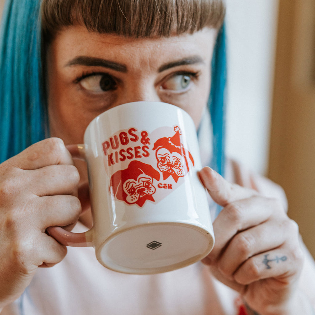 Candy & Kitsch 'Pugs and Kisses' branded mug is held by Jess in a kitschy vintage home.