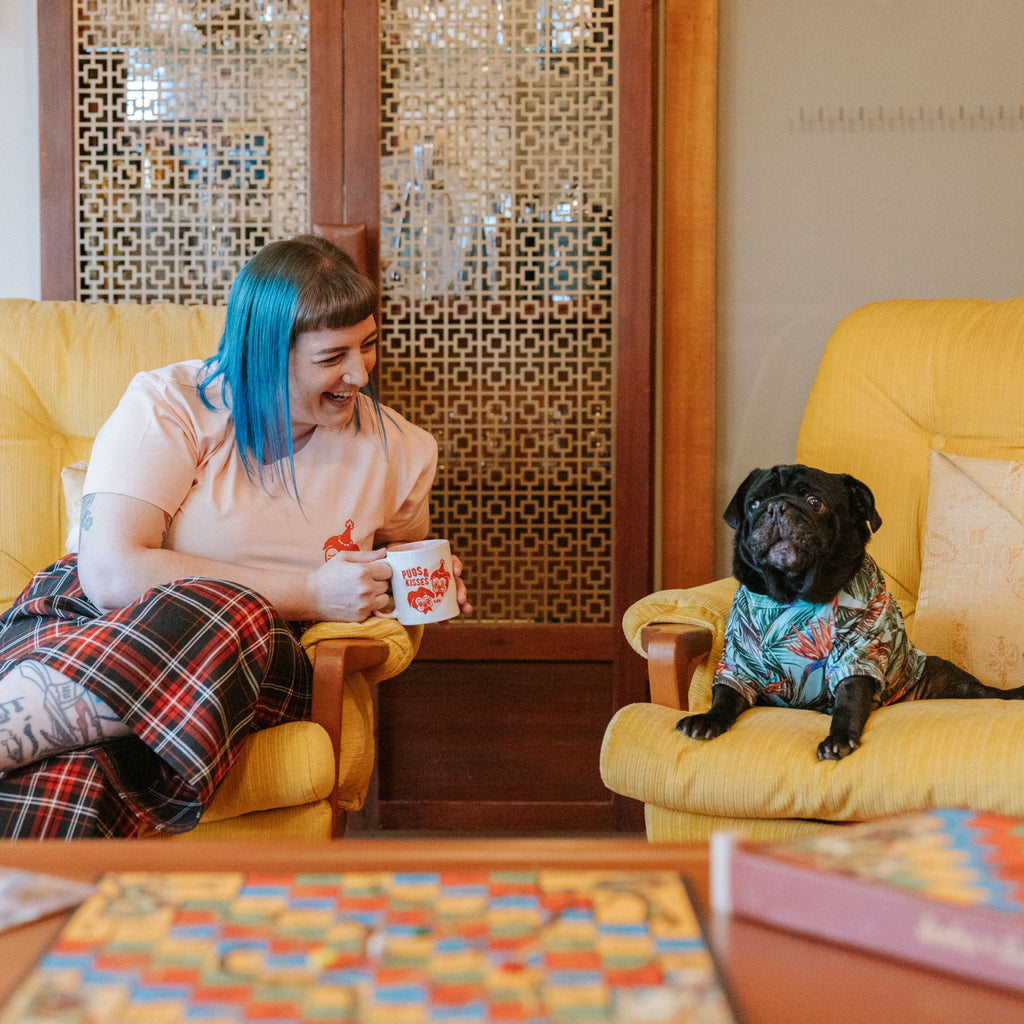 Candy & Kitsch 'Pugs and Kisses' branded mug is held by Jess in a kitschy vintage home.